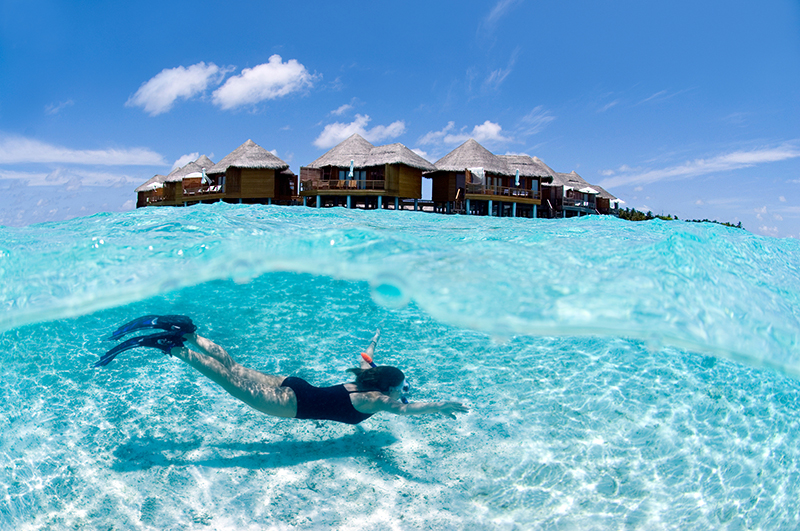 Feng Shui view of a snorkeller swimming in front of water villas in the Maldives.